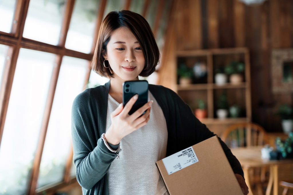 Smiling young Asian woman shopping online with smartphone on hand, Engineer open ERP(Enterprise Resource Planning) System in Singapore Smiling young Asian woman shopping online with smartphone on hand, Engineer open ERP(Enterprise Resource Planning) System in Singapore